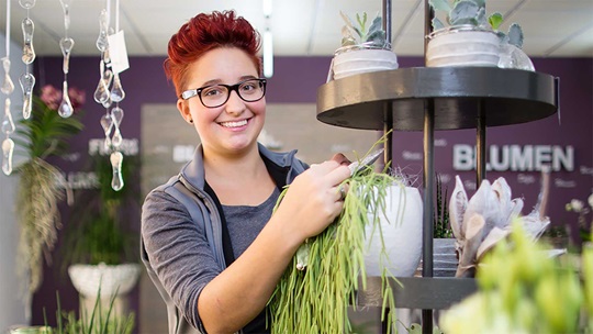Eine Floristin steht bei einer Topfpflanze