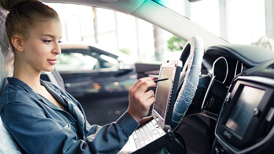 Eine Automechatronikerin analysiert den Boardcomputer eines Autos