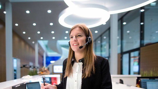 Eine Kauffrau steht am Empfangsdesk und telefoniert