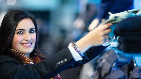 Eine Detailhandelsfachfrau legt ein Kleidungstück ins Regal zurück