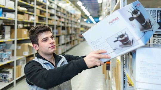 Ein Logistiker nimmt ein Packet aus dem Regal