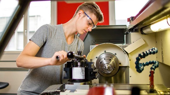 Ein Polymechaniker steht an einer Fräsmaschine