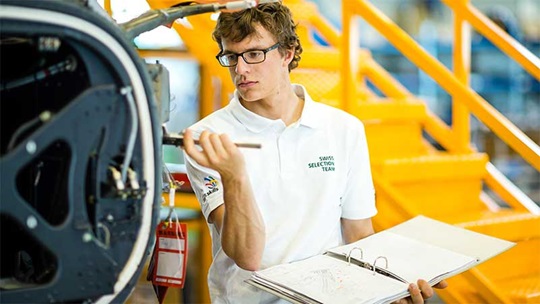 Ein Konstrukteur steht neben einem Flugzeug und überprüft mit einer Schieblehre die Masse