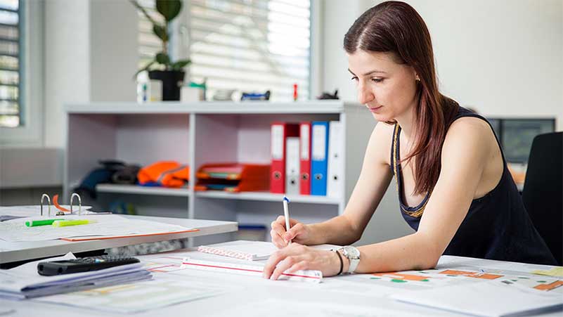 Eine Zeichnerin studiert Pläne auf Papier in ihrem Büro