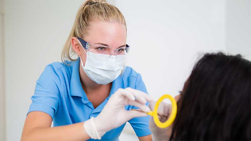 Eine Dentalassistentin bereitet an einer Kundin das Röntgen vor