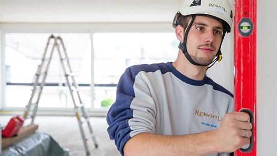 Zimmermann hält Wasserwage in der Hand und überprüft senkrechte Wand