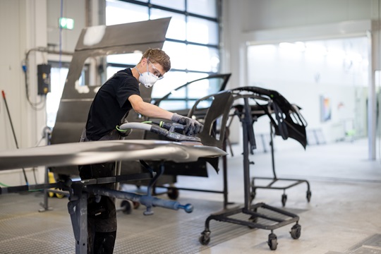 Ein Carrosserielackierer schleift eine Autotür ab