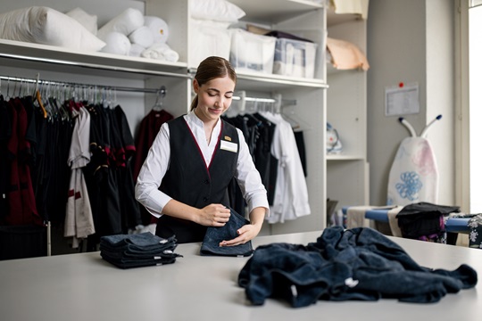 Eine Hotelfachfrau faltet Frotteewäsche
