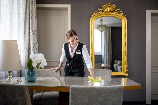 Eine Hotelfachfrau reinigt Tisch im Hotelzimmer