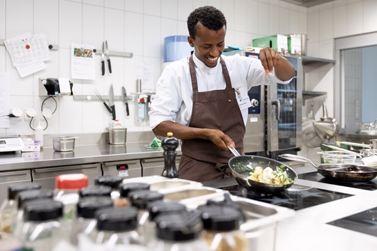 Ein Koch brät Kartoffeln in einer Bratpfanne
