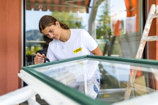 Eine Malerin malt einen Fensterrahmen