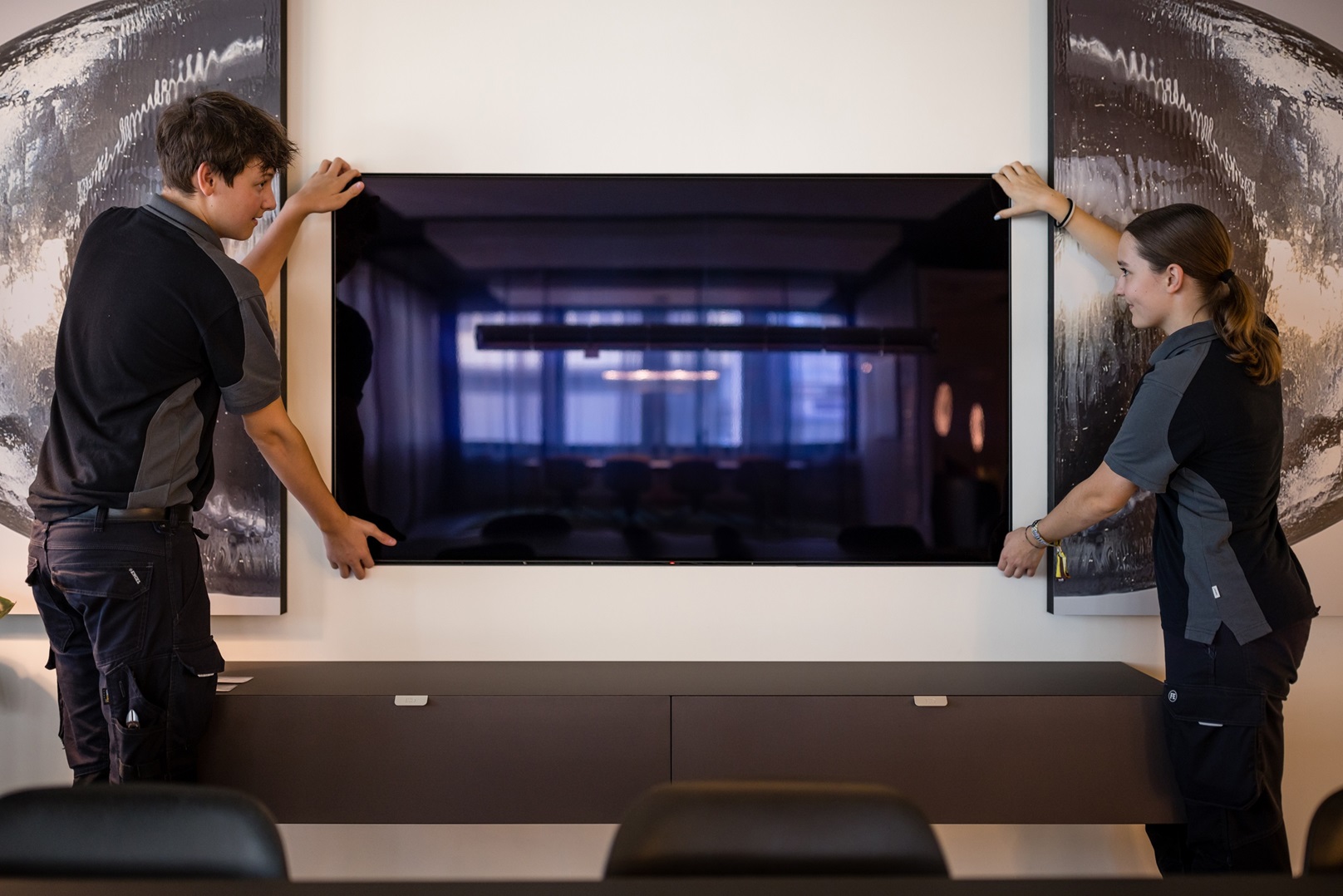 Zwei Multimediaelektroniker beim montieren eines Bildschirms