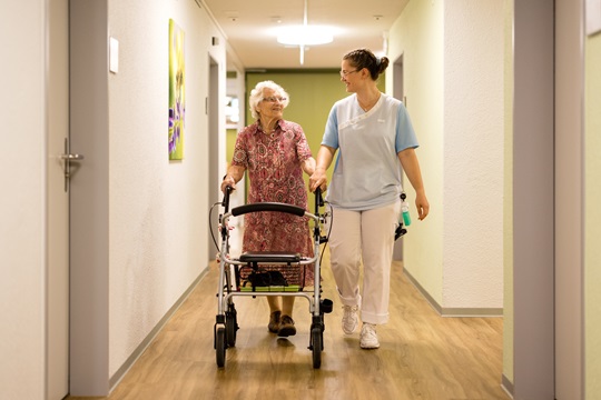 Fachfrau Gesundheit begleitet eine Seniorin