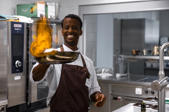 Koch flambiert Fleisch in der Pfanne