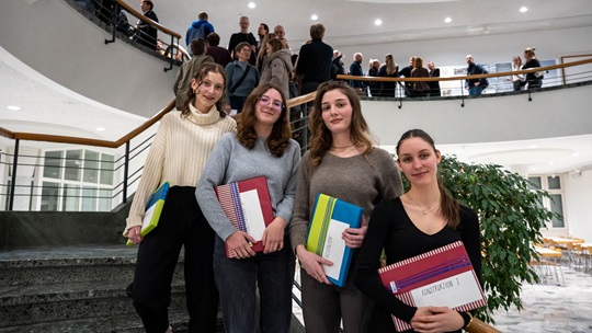 Vier Lernende stehen auf der Treppe. Sie halten ein Geschenk in der Hand, welches sie für ihre Projektarbeit erhalten haben.
