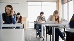 Lernende sitzen an Pulten und arbeiten konzentriert.