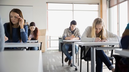 Lernende sitzen an Pulten und arbeiten konzentriert.